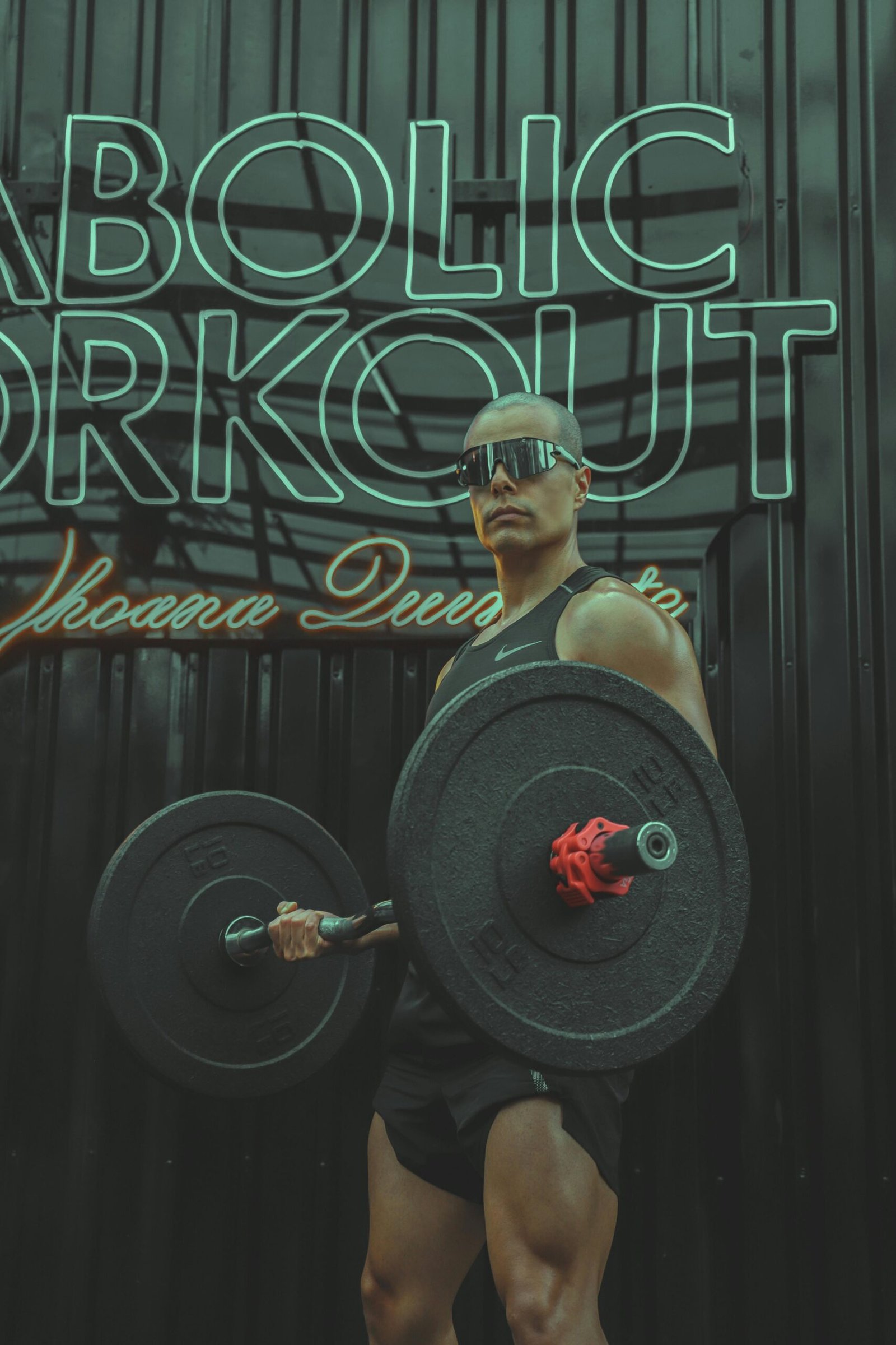 Muscular man in sunglasses lifting barbell indoors in a gym.