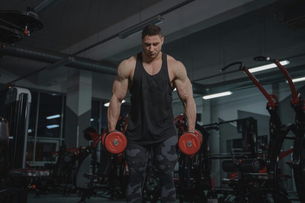 A strong man working out in a gym, lifting dumbbells with focus and intensity.