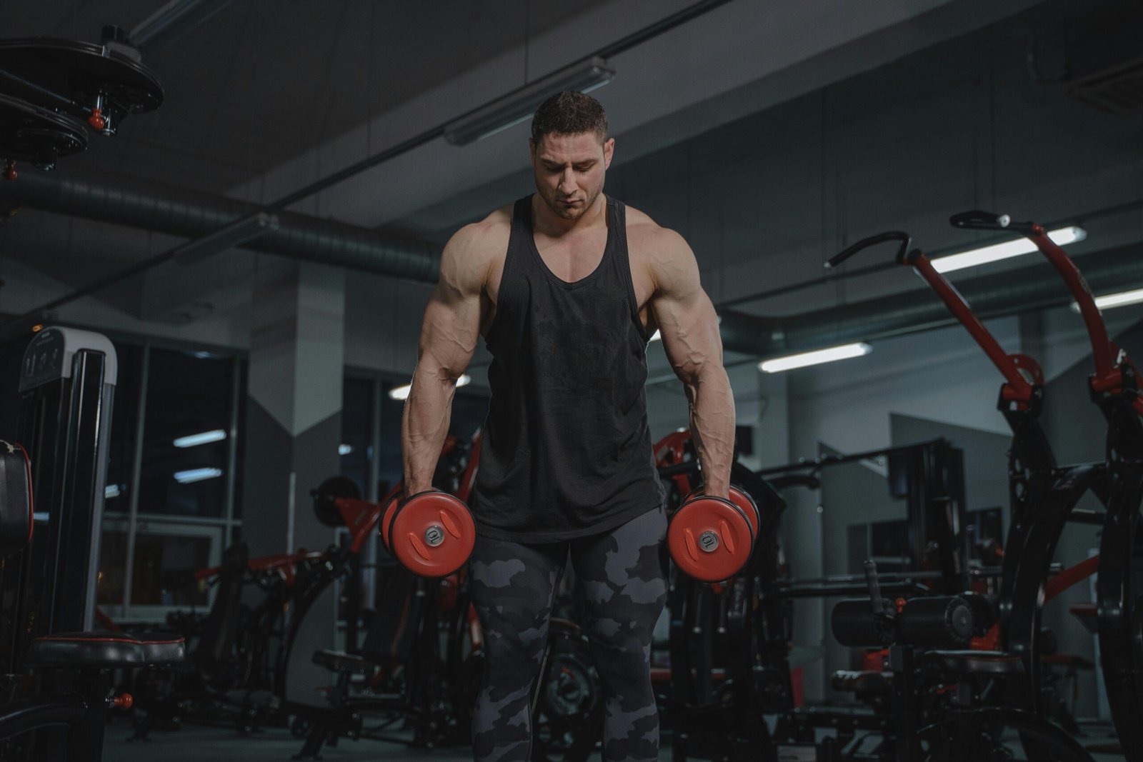 A strong man working out in a gym, lifting dumbbells with focus and intensity.